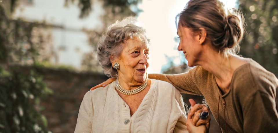 joyful adult daughter greeting happy surprised senior mother in garden